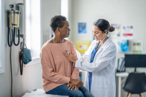Older woman getting an annual physical exam with her family medicine doctor.