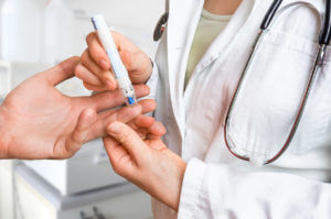 Family medicine doctor performing a blood glucose test on a patient with a finger stick.